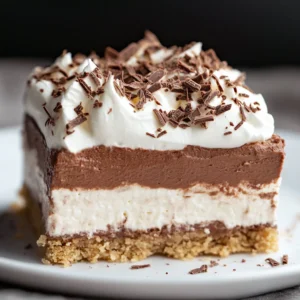 Easy Chocolate Delight DTI 4 A close-up of a beautifully layered Easy Chocolate Delight DTI with a graham cracker crust, creamy white and chocolate layers, topped with whipped cream and chocolate shavings.