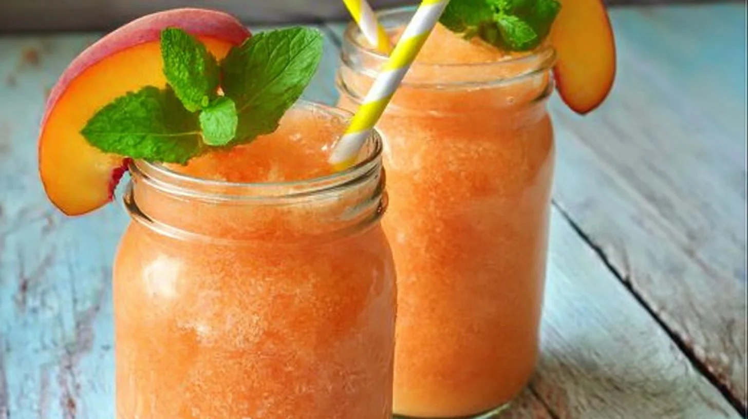 Delicious Peach Lemonade Slush in a glass with fresh peach slices