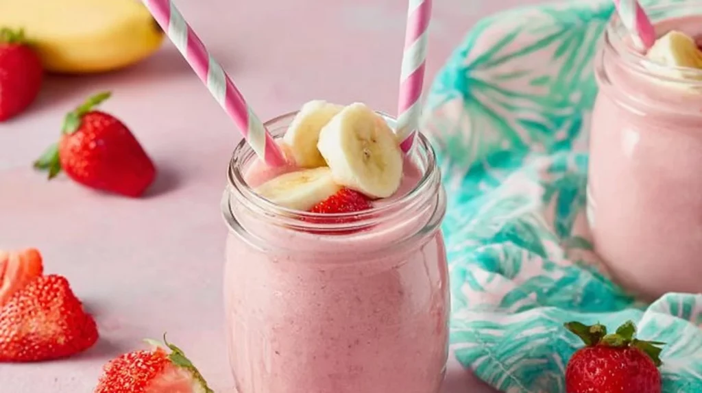 Healthy strawberry banana smoothie in a glass with fruits and mint garnish